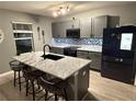 Modern kitchen featuring gray cabinets, stainless steel appliances, and a stylish island with bar seating at 451 Hartford Heights St, Spring Hill, FL 34609
