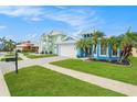 Bright blue home with white trim, complemented by lush landscaping, vibrant green lawns, and a paved driveway at 6408 Key Island Ave, Apollo Beach, FL 33572