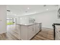 Open-concept kitchen offers an island with a sink and stainless steel dishwasher, flowing into the living area at 6690 Michael Favor Way, Wesley Chapel, FL 33545