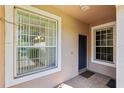 Exterior shot of front entrance with storm door, tan siding, and brick floor at 31447 Shaker Cir, Wesley Chapel, FL 33543