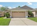 A beige two-car garage on a sunny day with green grass at 31447 Shaker Cir, Wesley Chapel, FL 33543
