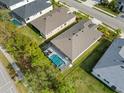 An aerial view of a property featuring a screened-in pool, manicured lawn, and a well-maintained roof at 12739 Rainwashed Loop, Parrish, FL 34219