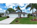 Beautiful home with a well-maintained lawn, palm trees, and a convenient two-car garage at 609 Fort Duquesna Dr, Sun City Center, FL 33573