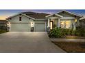 Charming single-Gathering home featuring a three-car garage, landscaped yard, and inviting front porch with stone accents at 6189 Hidden Branch Dr, Apollo Beach, FL 33572