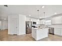 Modern kitchen features white cabinets, stainless steel appliances, and a central island with pendant lighting at 12811 Wanderlust Pl, Parrish, FL 34219