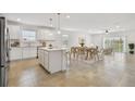 Open concept living room featuring a modern kitchen, dining area, and a sitting space with large windows at 12811 Wanderlust Pl, Parrish, FL 34219