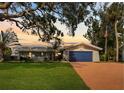Charming single-story home features a well-manicured lawn, lovely landscaping and a bright blue garage door at 1985 Byram Dr, Clearwater, FL 33755