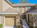 Close-up of a two-story townhome entrance featuring a garage, walkway, and neutral exterior at 4207 Key Thatch Dr, Tampa, FL 33610