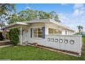 A well-maintained home featuring a white exterior, blue shutters, and a quaint front yard with lush green grass at 51 Lexington Dr, Dunedin, FL 34698