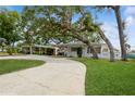 Beautiful single-story home featuring a curved driveway and a lush green lawn, framed by mature trees at 51 Lexington Dr, Dunedin, FL 34698