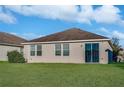 A lush green backyard featuring sliding glass doors, windows, and a well-manicured lawn at 814 Fern Leaf Dr, Ruskin, FL 33570