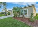 Side view of a home with mulch beds with green plants, grass, and windows at 814 Fern Leaf Dr, Ruskin, FL 33570