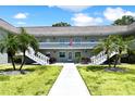 Charming condominium complex featuring a neatly manicured lawn, palm trees, and white staircases leading to the second floor at 1250 S Pinellas Ave # 713, Tarpon Springs, FL 34689