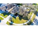 An aerial perspective reveals a well-maintained home with a green lawn, mature trees, and a welcoming entrance at 5215 New Brittany Ln, Zephyrhills, FL 33541