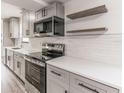 Bright kitchen features stainless steel appliances, white cabinets, and floating shelves at 3721 9Th S Ave, St Petersburg, FL 33711