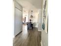 View of hallway with gray wood floors, leading to a dining area and living room with blue sofa at 4684 25Th S Ave, St Petersburg, FL 33711