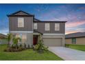 Charming two-story home with a well-manicured lawn and a two-car garage, complemented by a colorful sky at 11307 Linden Depot Rd, San Antonio, FL 33576