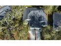 Aerial view of a well-maintained home with a large roof, surrounded by lush trees and a neatly kept lawn at 12411 Cavalier Ct, Hudson, FL 34669
