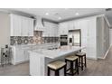 Modern kitchen features white cabinetry, quartz countertops, a tile backsplash, and stainless steel appliances at 19891 Bridgetown Loop, Venice, FL 34293