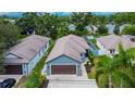 Aerial view of a blue single-story home featuring a large garage, lush greenery, and well maintained landscaping at 3369 Houle Ave, Sarasota, FL 34232