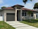 Charming single-story home featuring a gray garage door, tan stucco and manicured lawn at 7206 N Glen Ave, Tampa, FL 33614