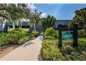 Condo building exterior showcasing mature landscaping and signage, creating a serene entrance at 36750 Us Highway 19 # 21-301, Palm Harbor, FL 34684