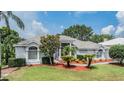 A charming single-story home with a beautifully landscaped front yard, decorative shrubbery, and a concrete walkway at 394 Tall Oak Trl, Tarpon Springs, FL 34688