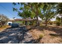 View of the front of the home with mature trees, a driveway, and a tidy front yard at 9439 Sun Isle Ne Dr, St Petersburg, FL 33702