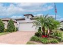 Charming home featuring a brick driveway, manicured lawn, and a two-car garage at 19367 Coastal Shore Ter, Land O Lakes, FL 34638