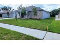 A wide view of a single-story home featuring a brick facade, manicured lawn, and a long driveway at 422 Shannon Estates Ct, Plant City, FL 33563