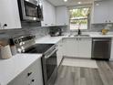 Modern kitchen featuring stainless steel appliances, white cabinets and white quartz countertops and gray backsplash at 11592 110Th Ter, Seminole, FL 33778