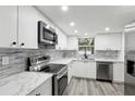 Modern kitchen featuring stainless steel appliances, white cabinets and white quartz countertops and gray backsplash at 11592 110Th Ter, Seminole, FL 33778