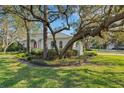 Beautiful home featuring a well-manicured lawn, mature trees, and a charming red front door at 2850 Deer Run, Tarpon Springs, FL 34688