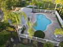 An aerial view of community pool and lounge area surrounded by landscaping and a white fence at 558 Harbor Ridge Dr, Palm Harbor, FL 34683