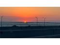 Beautiful sunset over the water with orange glow and silhouetted cars at 3987 Maceachen Blvd # 133, Sarasota, FL 34233