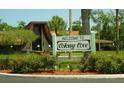 Welcome sign to Colony Cove surrounded by lush landscaping in front of an architecturally unique building at 5142 Serene Sq, New Port Richey, FL 34653