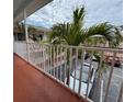 Exterior view from balcony with white railing overlooking parking area and palm trees at 19417 Gulf Blvd # C210, Indian Shores, FL 33785