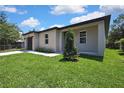 Exterior shot of the home showcasing the manicured lawn, minimalist landscaping, and the neutral exterior paint at 10019 N Hyaleah, Tampa, FL 33617