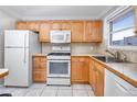Functional kitchen with white appliances, light wood cabinets, and durable tile flooring at 6025 Shore S Blvd # 311, Gulfport, FL 33707