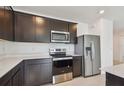 Kitchen with stainless steel appliances, dark cabinetry, and light countertops at 12815 Wanderlust Pl, Parrish, FL 34219