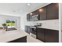 Bright kitchen with stainless steel appliances, dark cabinetry, and a view of the outdoors at 12819 Wanderlust Pl, Parrish, FL 34219