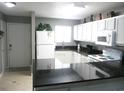 A kitchen featuring black countertops, ceramic tile flooring, white cabinets and appliances at 6033 34Th W St # 45, Bradenton, FL 34210