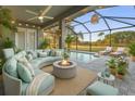 Inviting screened patio with plush seating, a cozy fire pit, and a refreshing pool overlooking lush landscaping at 10920 Flint Estates Dr, Thonotosassa, FL 33592