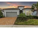 Charming single-story home featuring a brick driveway, lush landscaping, and a two-car garage at 19771 Ship Wheel Way, Land O Lakes, FL 34638