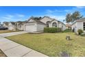 Well-maintained single-Gathering home featuring a neatly kept lawn and a paved driveway leading to a garage at 4605 Lisette Cir, Brooksville, FL 34604