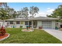 Charming single-story home featuring a well-manicured lawn, solar panels, and colorful landscaping at 1611 San Charles Dr, Dunedin, FL 34698