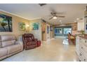 Bright living room with ceiling fan, tiled floors, and adjacent eat-in kitchen at 1611 San Charles Dr, Dunedin, FL 34698