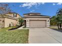Beige two-story home with a two car garage, manicured lawn, and minimal landscaping at 12610 Geneva Glade Dr, Riverview, FL 33578
