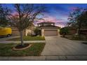 Two-story home with a large driveway, well-kept lawn and mature landscaping under a dramatic sunset sky at 12610 Geneva Glade Dr, Riverview, FL 33578