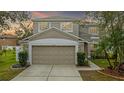 Two-story home with a two-car garage, neutral paint, green landscaping, and a concrete driveway at 10525 Lucaya Dr, Tampa, FL 33647